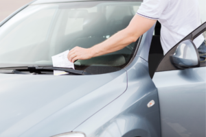 Man grabbing parking ticket off his care.