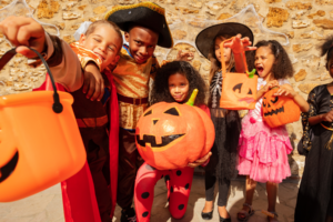 Children wearing costumes and holding out pumpkin buckets.