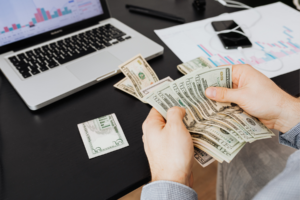 Man going through a stack of cash with graphs in the background.