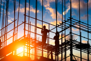 Construction workers building in front of a sunset.