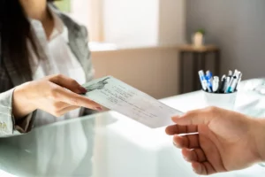 Woman handing someone a check across a table.