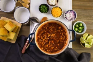 Bowl of chili surrounded by bowls of toppings.