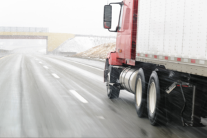 Semi truck driving on a snowy road.