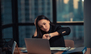 Woman looking at her watch in her office at night.