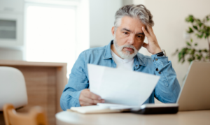 Man looking at papers with his head in his hand.