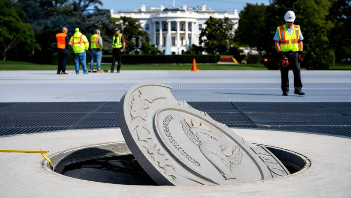 Crews remove the granite seal on the White House helipad, signaling potential project delays