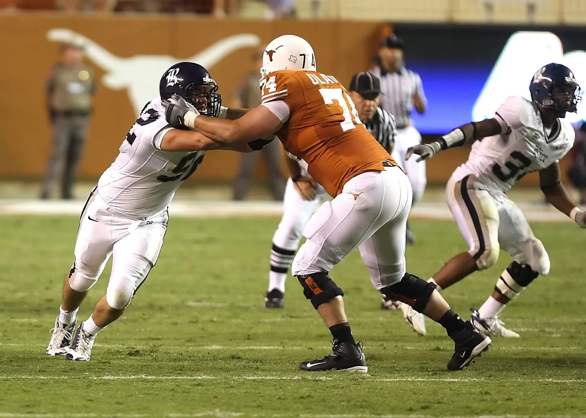Offensive linemen attempting to block defensive pressure during a college football game