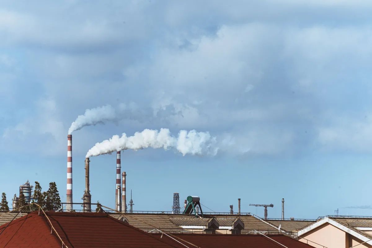 Industrial facility with smoke stacks emitting emissions into the sky
