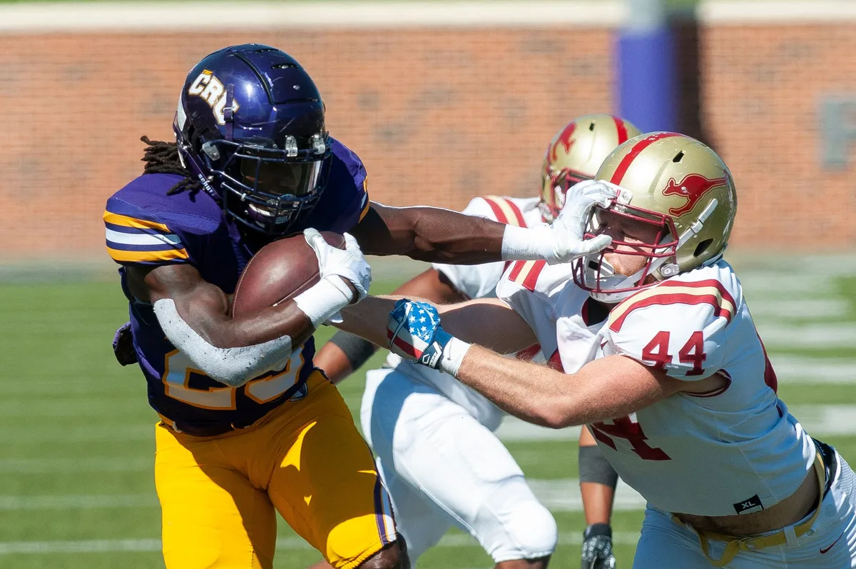Defensive linemen engaging in run defense during a college football game.