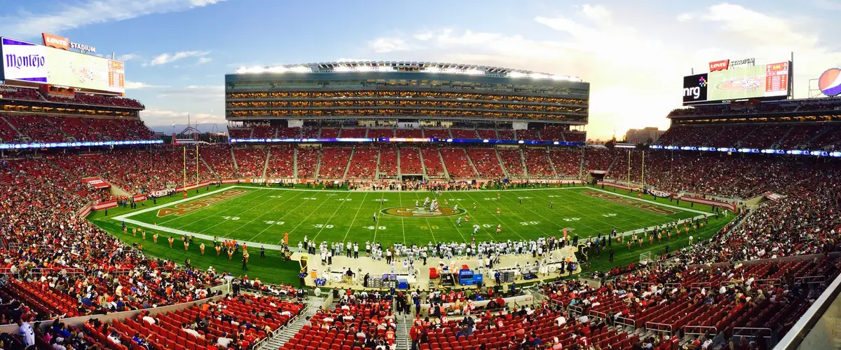 NFL players competing in a divisional matchup under stadium lights during a high-stakes game.