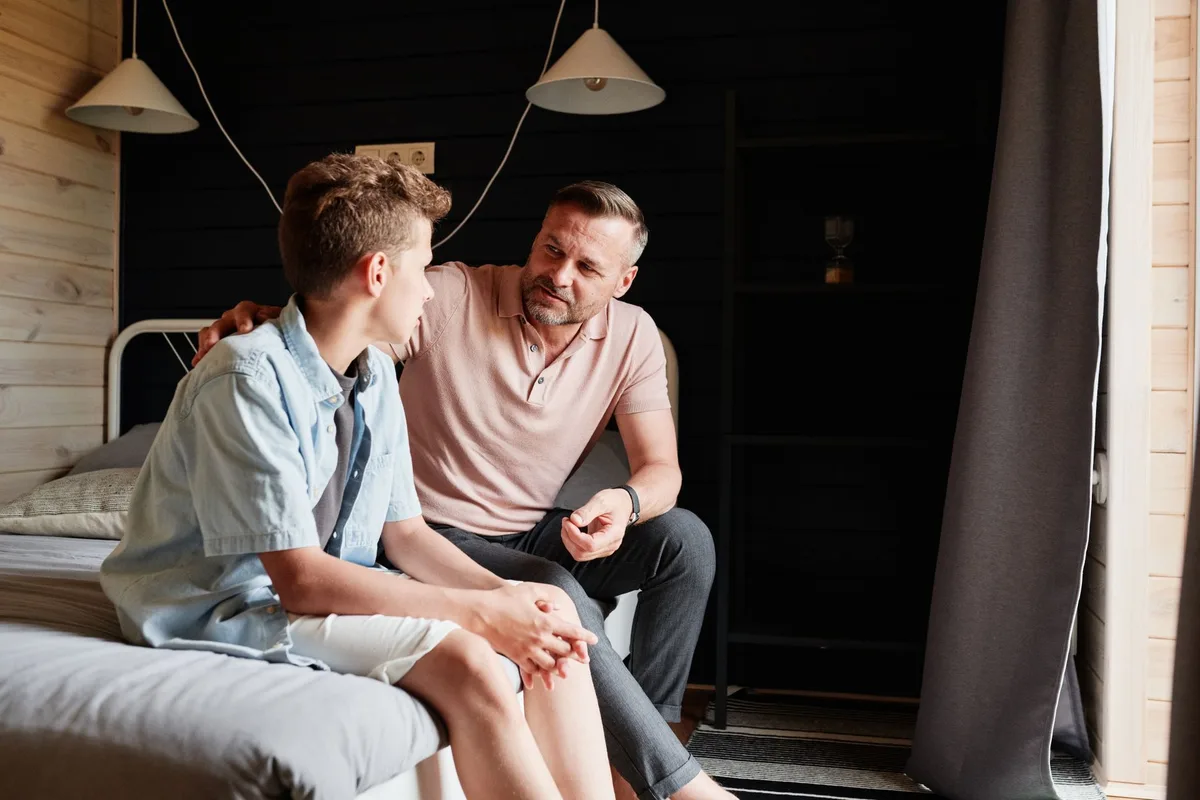 Parent and teenager having discussion at home about device and online safety