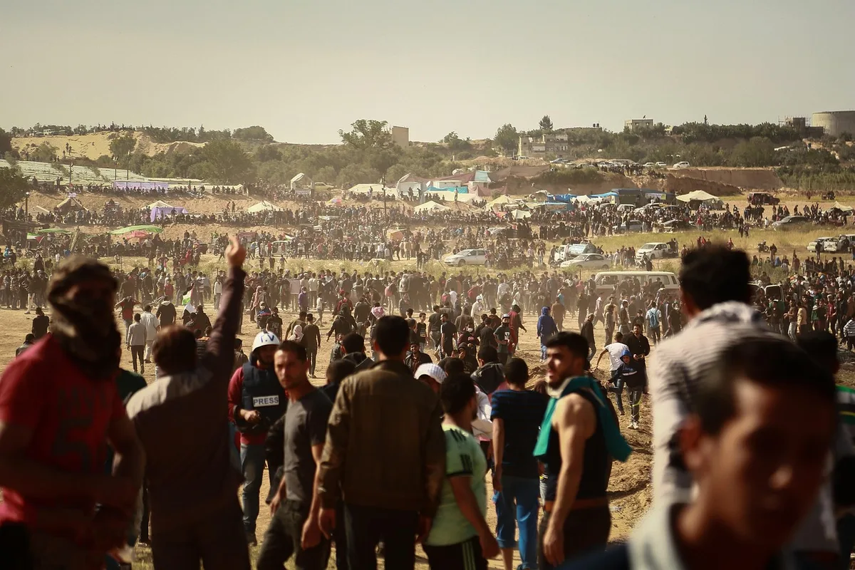 Crowd of supporters at a political rally with raised hands and flags