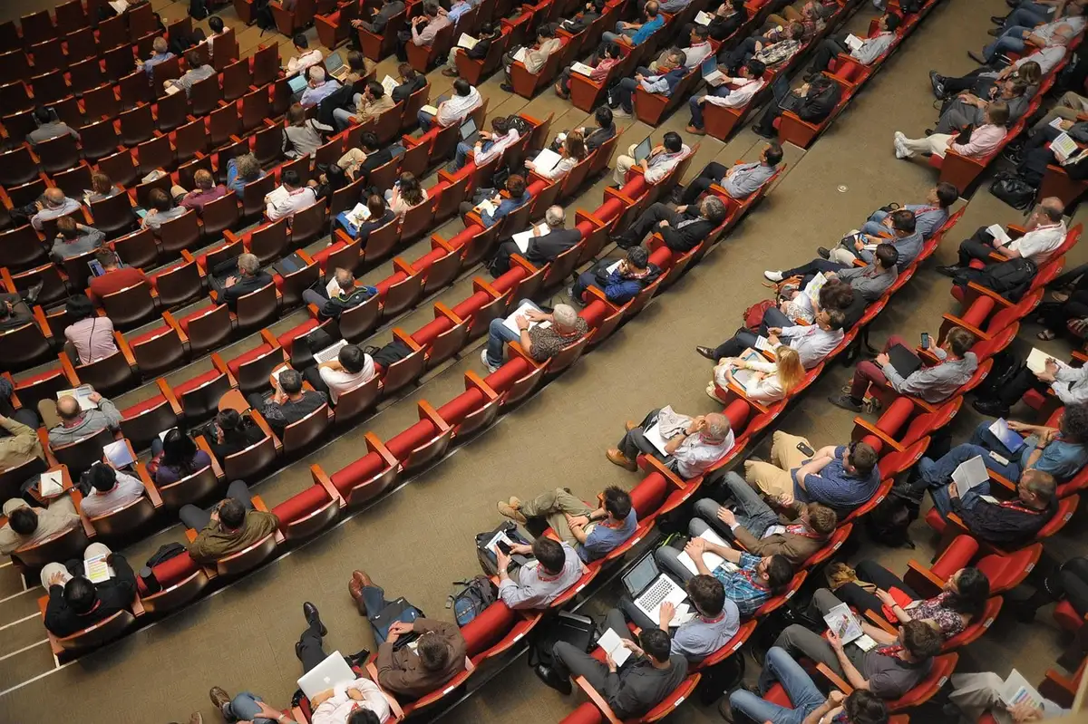 Journalists and media representatives at a film festival press conference, cameras focused on speakers on stage.