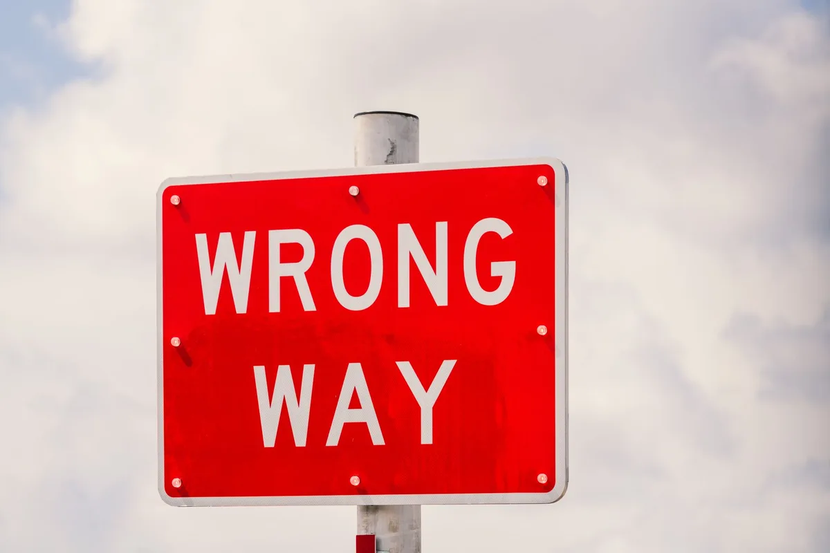 Road sign warning of wrong-way traffic with median barrier visible