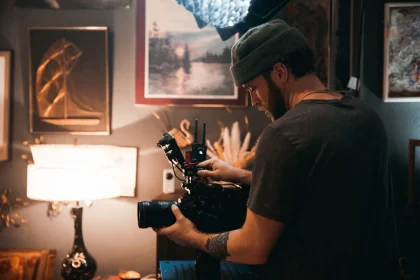 Filmmaker's hands holding camera equipment and script pages at a creative workspace