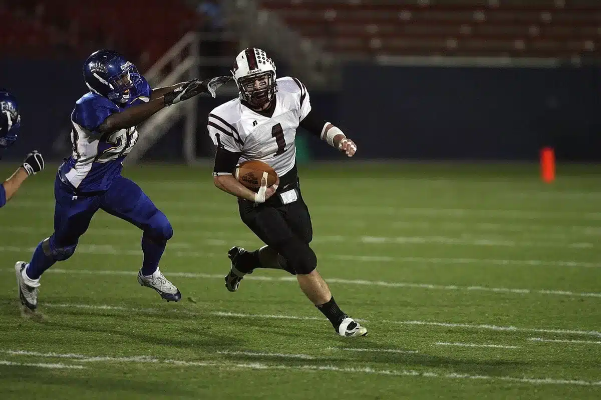Quarterback dropping back amid receivers against a stadium backdrop