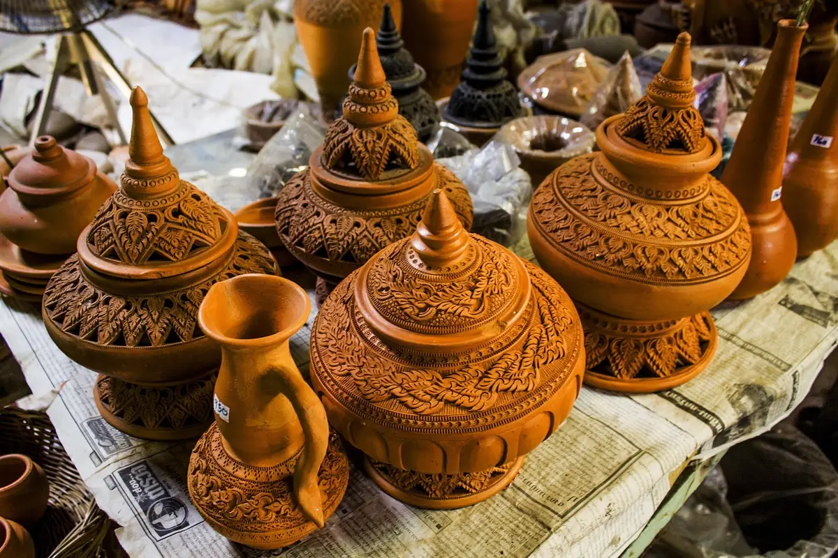 Outdoor farmers market stall beside a pottery workshop table at a community park