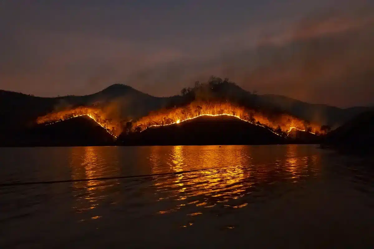 Firefighting crews and aircraft responding to active wildfire with smoke visible across landscape