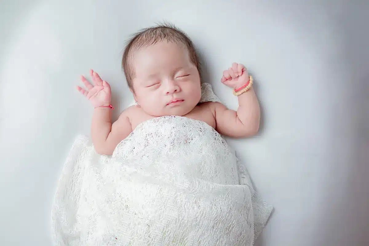 Infant sleeping on a firm crib mattress with no loose bedding