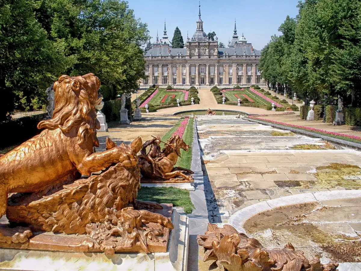 View of a public plaza with a large abstract sculpture and arriving visitors