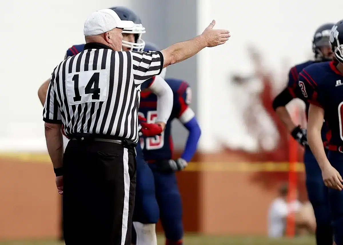 Officials reviewing a close football game call on the field during a dispute over the final score.