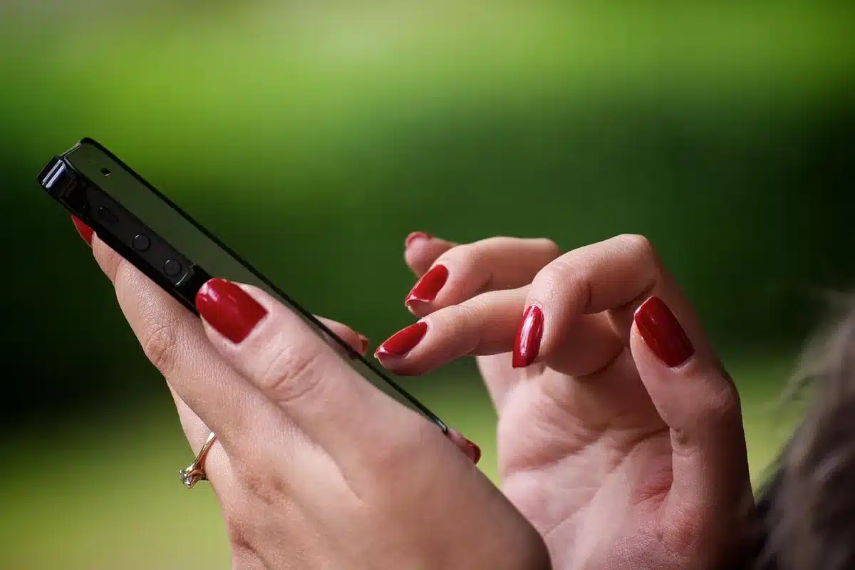 Hands of a caregiver holding a phone, appearing stressed and isolated