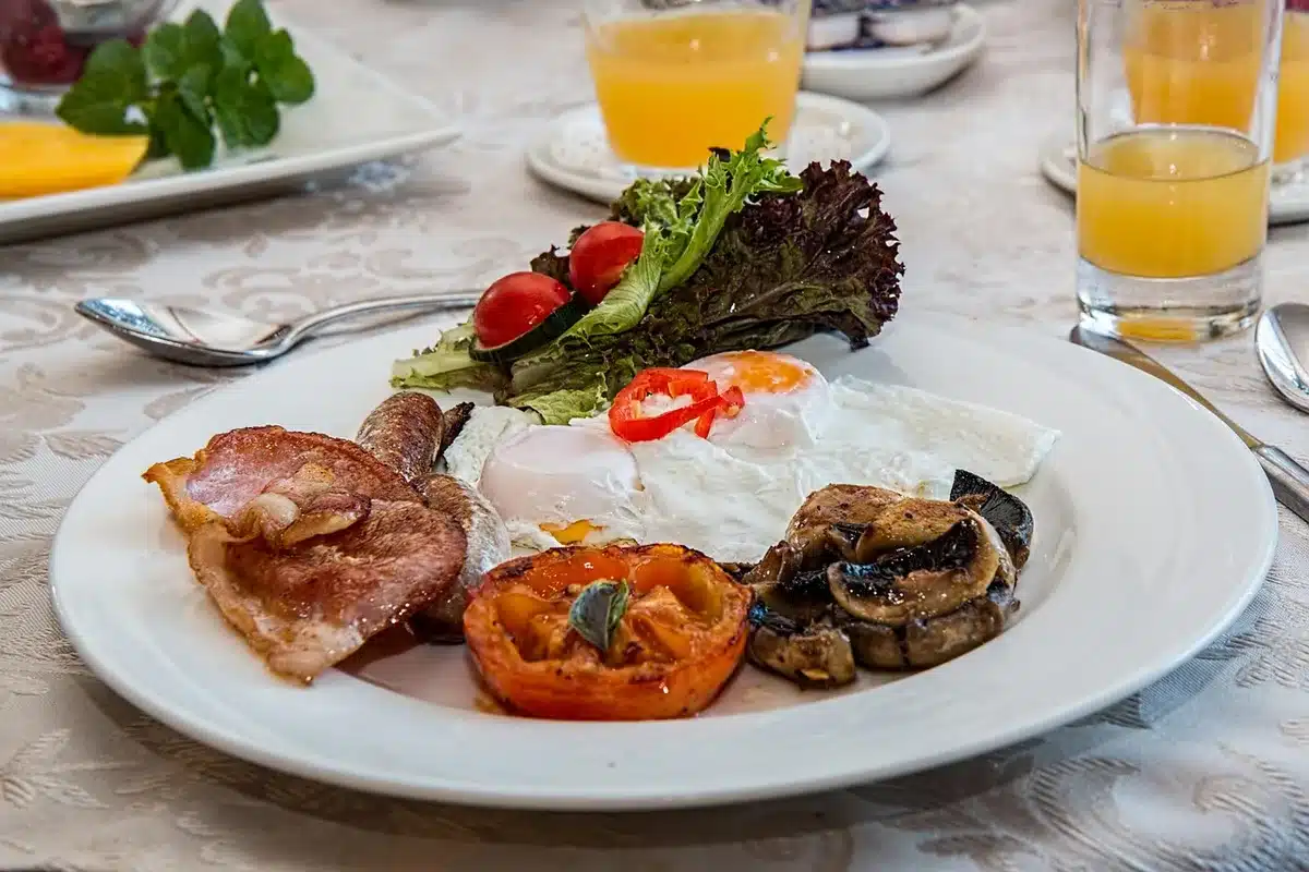 A balanced meal plate with grilled chicken, roasted vegetables, and greens on a white plate in a home kitchen setting