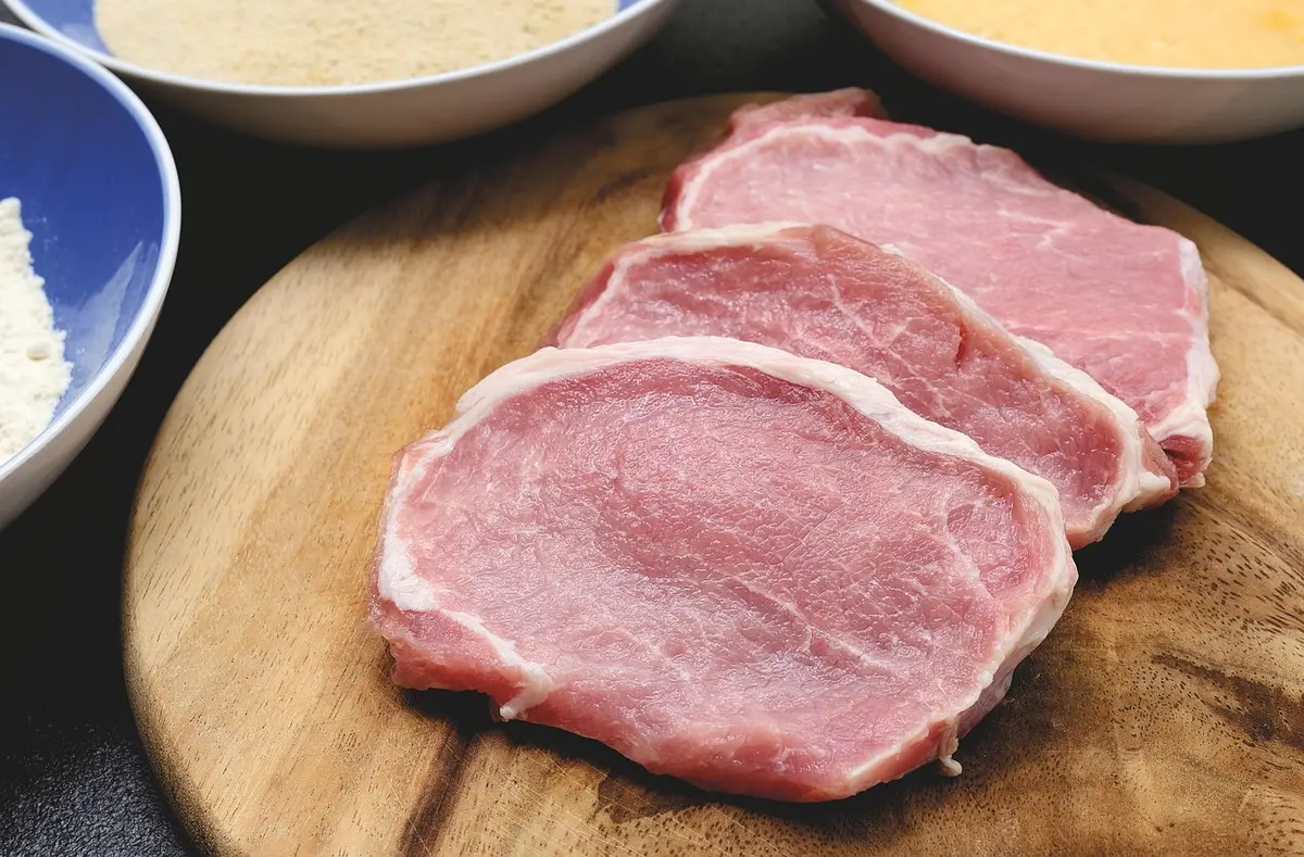 Variety of raw red meat cuts on a butcher's board showing beef, pork and lamb
