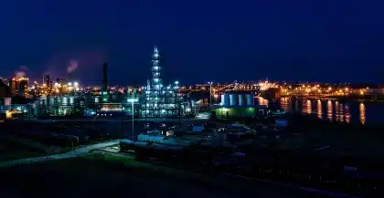 Silhouette of an industrial chemical tank with emergency lights at dusk