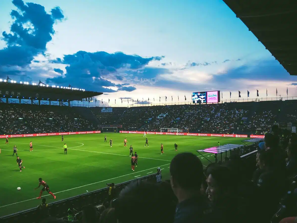 Players contesting a pass in the end zone with fans reacting
