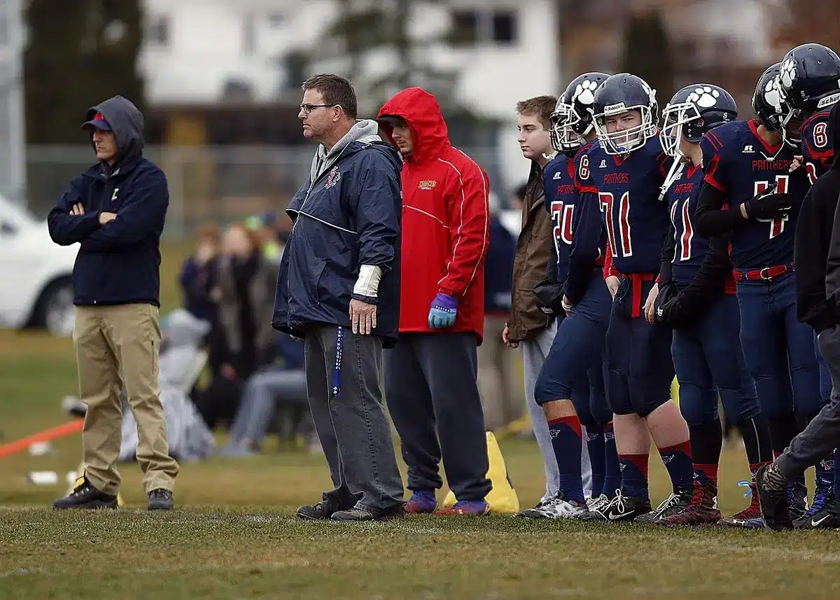 Coach with headset studying play card on the sideline