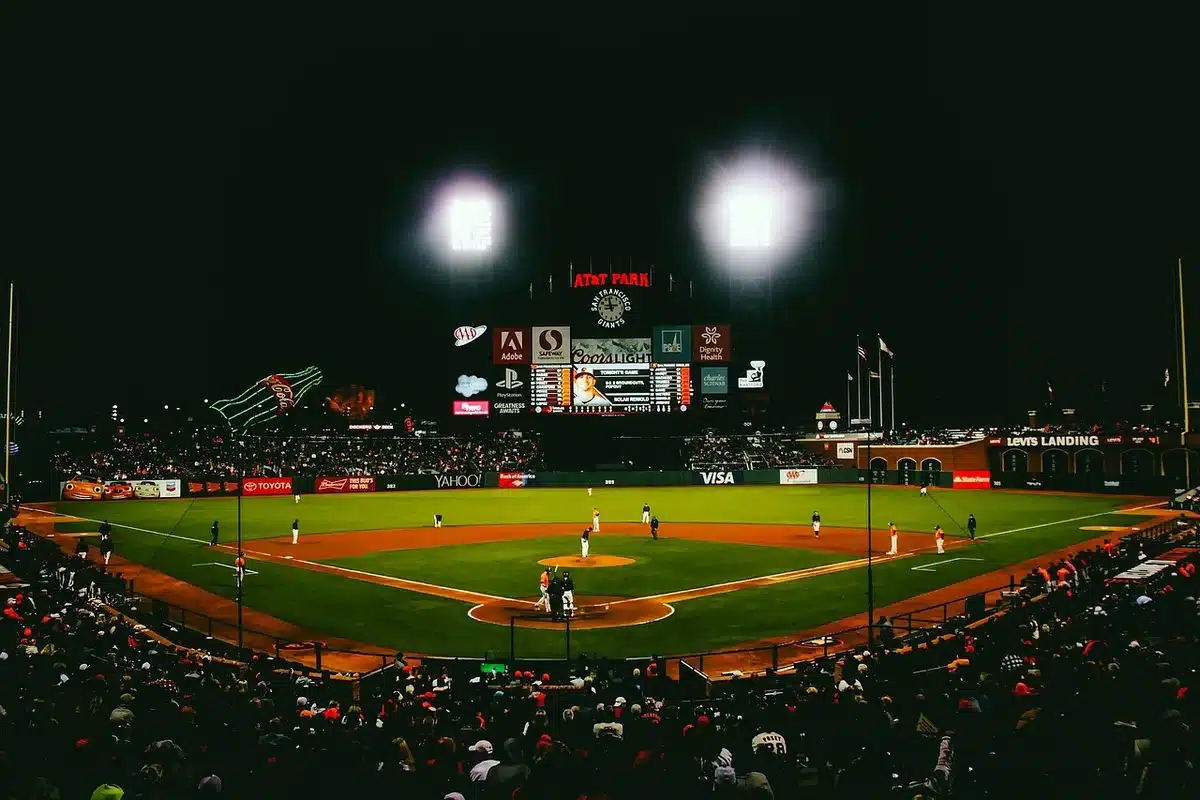 Silhouetted fans in a stadium with a helmet on a dugout bench